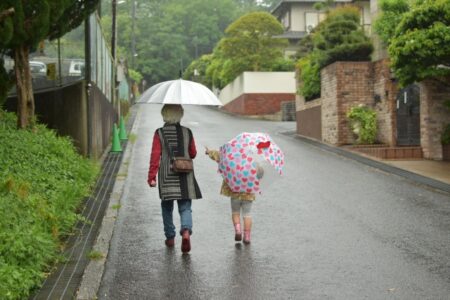 傘をさして散歩する祖母と孫